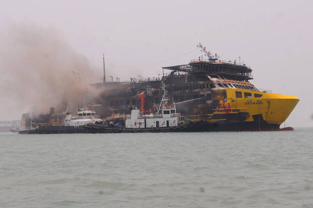Efforts are underway to extinguish a fire that broke out on a passenger ferry in Indonesia s Cilegon PELABUHAN MERAK, CILEGON, INDONESIA - OCTOBER 21: Fireboats take turns spraying water onto the passenger ferry KMP Batumandi to cool down the vessel after it caught fire while preparing to dock off Merak Port in Cilegon, Banten, Indonesia on Wednesday, October 21, 2026. The vessel caught fire on Tuesday, October 20, and rescue operations remain underway as the ship continues to emit smoke. Water is continuously sprayed to cool the vehicle deck containing numerous cars, motorcycles, buses, and trucks, while authorities confirm no fatalities have been reported. Dasril Roszandi Anadolu Pelabuhan Merak Indonesia. Editorial use only. Please get  Copyright: x2026xAnadoluxDasrilxRoszandix