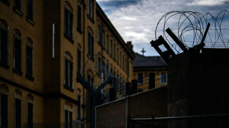 21.10.2026, Deutschland,Sachsen, Bautzen : Eine Überwachungskamera und eine Straßenlaterne vor den historischen Gebäuden der Justizvollzugsanstalt Bautzen in Sachsen. Die Gefängnisanlage ist durch Mauern und Sicherheitszäune gesichert.
