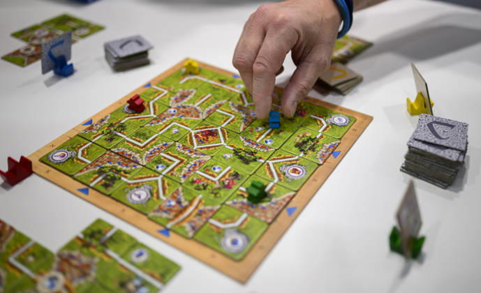 Feature, das Spiel Carcassonne Labyrinth aus der Verlagskooperation Ravensburger und Hans im Glück, eine Hand zieht einen Spielstein, Neuheitenschau, am 21.10.2026 Messe SPIEL Essen vom 22.10 - 25.10.2026 in E s s e n Deutschland. Grugahalle