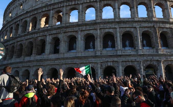 (261024) -- ROME, Oct. 24, 2026 -- Demonstrators march past the Colosseum during an anti-war march in Rome, Italy, Oct. 24, 2026. Protests over rising living costs, military expansion and increased arms spending swept across several Italian cities on Saturday, with clashes between demonstrators and police reported in multiple locations. In Rome, demonstrators set off from Piazza della Repubblica, according to the ANSA news agency. Clashes erupted between protesters and police in the city center later in the evening, prompting police to use water cannons and tear gas in an attempt to disperse the crowds. ) ITALY-ROME-PROTESTS WangxKaiyan