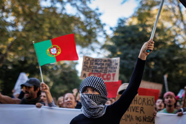 October 24, 2026, Lisbon, Portugal: A protester with her face covered raises a flag at the front line during the demonstration. People march through central Lisbon during a demonstration demanding affordable housing and protesting against the rising cost of living. The protest started at Marques de Pombal and ended at Rossio Square, where demonstrators set up tents at the end of the march in protest against Portugal s housing crisis. Lisbon Portugal - ZUMAs197 20261024_aaa_s197_589 Copyright: xHenriquexCasinhasx